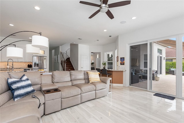 living area featuring recessed lighting, a ceiling fan, and stairs