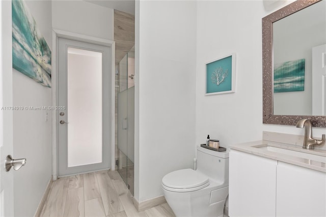full bathroom with vanity, baseboards, toilet, and a shower stall