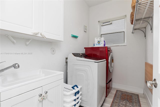 laundry room with washer and dryer, baseboards, a sink, cabinet space, and light wood finished floors