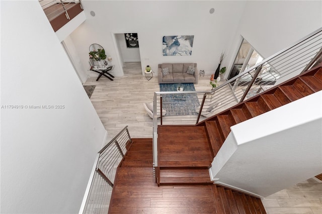 stairs featuring wood finished floors and a towering ceiling