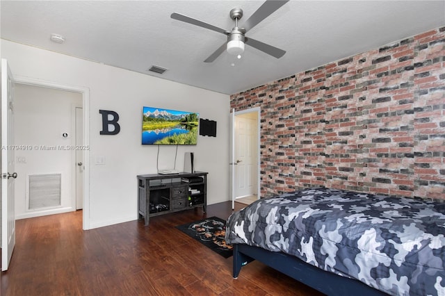 bedroom featuring visible vents, wood finished floors, and brick wall
