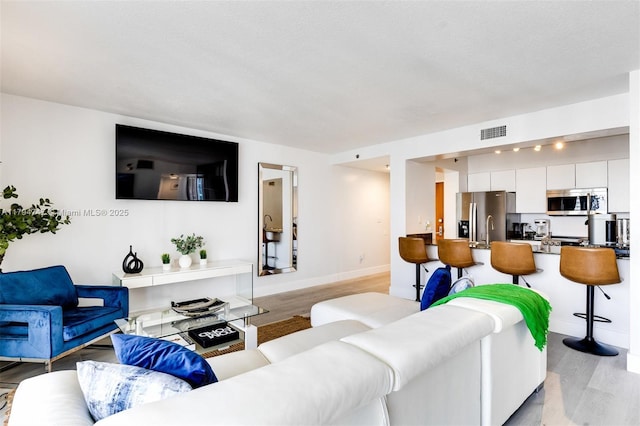 living area featuring baseboards, visible vents, and light wood-style floors
