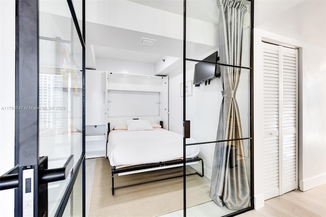 bedroom featuring baseboards, visible vents, wood finished floors, and a closet
