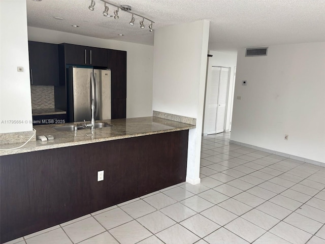 kitchen with baseboards, freestanding refrigerator, a textured ceiling, and a peninsula