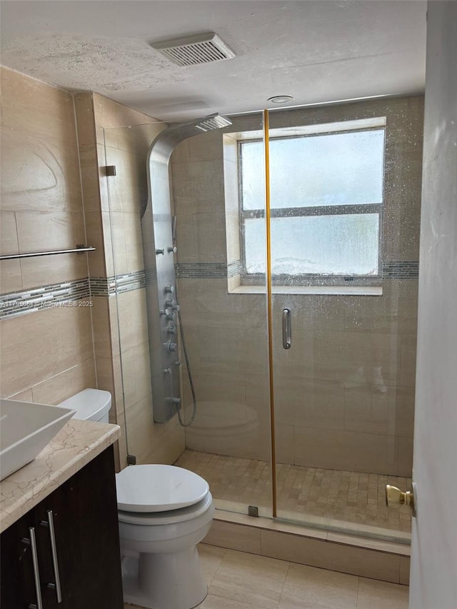 bathroom featuring visible vents, a shower stall, vanity, tile patterned floors, and toilet