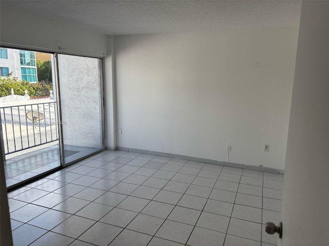 unfurnished room with light tile patterned floors, baseboards, and a textured ceiling