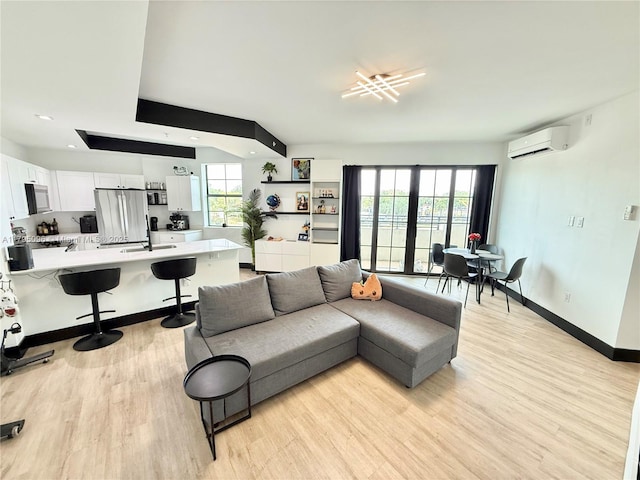 living room featuring light wood-style floors, baseboards, plenty of natural light, and a wall mounted air conditioner