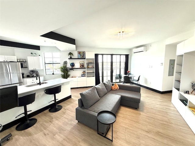 living room featuring light wood-style floors, a wall mounted air conditioner, baseboards, and electric panel