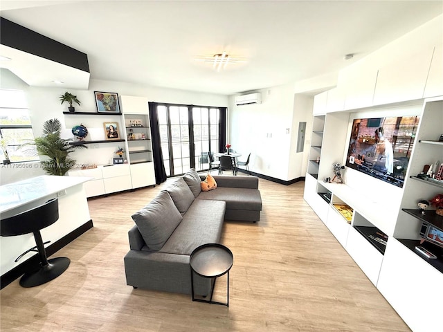 living room featuring an AC wall unit, plenty of natural light, built in features, and light wood finished floors