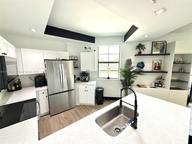 kitchen with white cabinets, a sink, light countertops, freestanding refrigerator, and baseboards