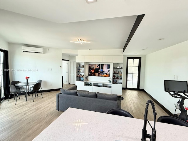 living room featuring baseboards, light wood-style floors, and a wall mounted AC