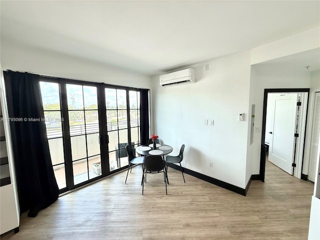 dining space featuring light wood-style floors, baseboards, and a wall mounted AC