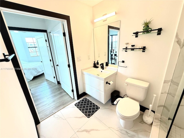 full bath with connected bathroom, vanity, toilet, marble finish floor, and baseboards