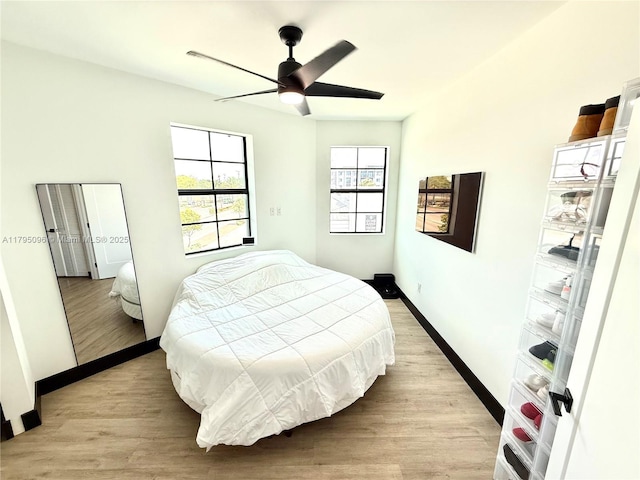 bedroom with baseboards, a ceiling fan, and light wood-type flooring