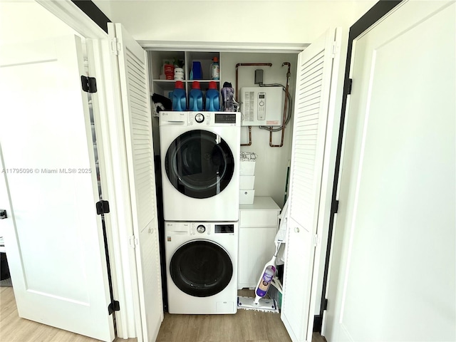 washroom featuring laundry area, stacked washer and dryer, and wood finished floors