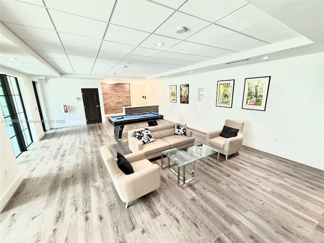 living room with baseboards, light wood-type flooring, and a paneled ceiling