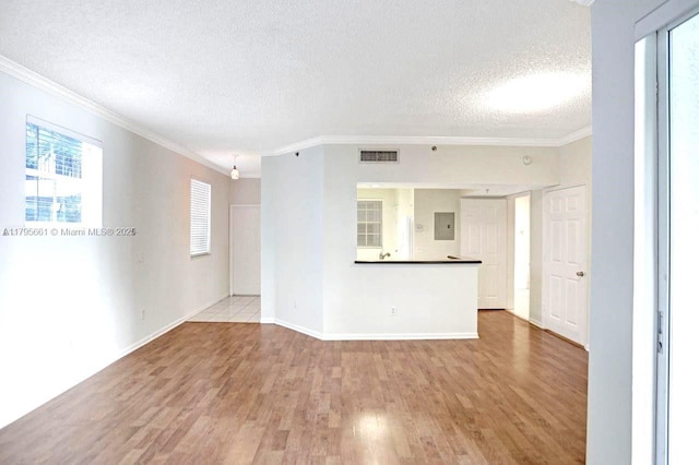unfurnished living room featuring a textured ceiling, baseboards, wood finished floors, visible vents, and ornamental molding