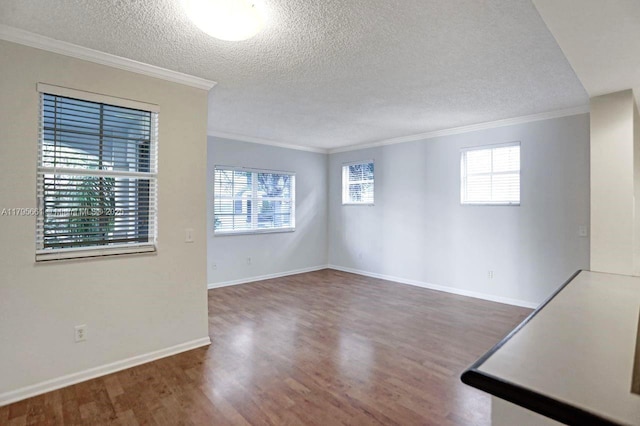 empty room with crown molding, a textured ceiling, and wood finished floors