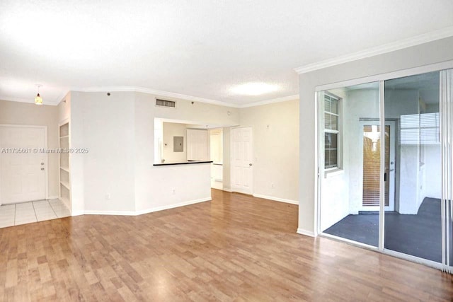 unfurnished living room with crown molding, baseboards, wood finished floors, and visible vents