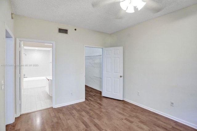 unfurnished bedroom with a textured ceiling, visible vents, wood finished floors, and a closet