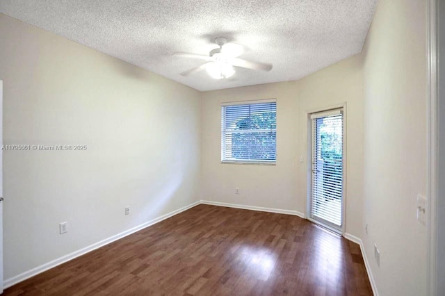 empty room with baseboards, a ceiling fan, a textured ceiling, and dark wood-type flooring