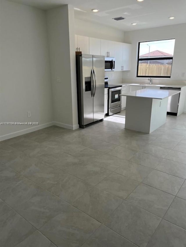 kitchen with visible vents, appliances with stainless steel finishes, a center island, a sink, and white cabinetry