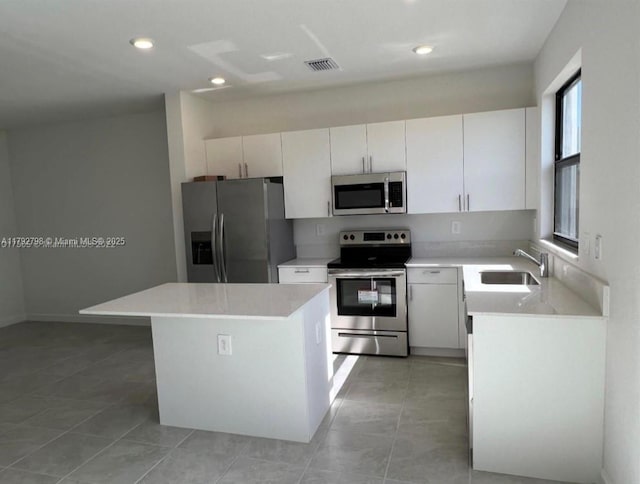kitchen featuring light countertops, appliances with stainless steel finishes, a kitchen island, and a sink