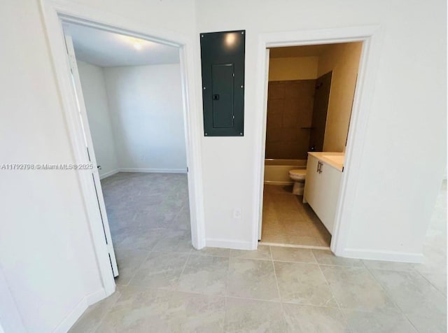 corridor featuring baseboards, light tile patterned floors, and electric panel