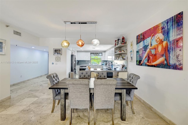 dining area with baseboards, stone finish floor, and visible vents