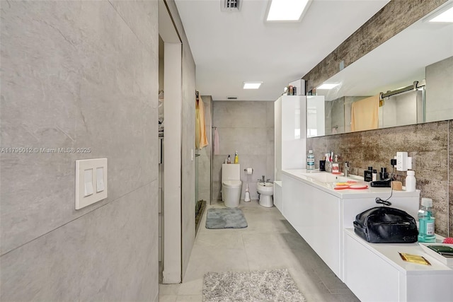 full bathroom featuring vanity, toilet, tile walls, a bidet, and a stall shower