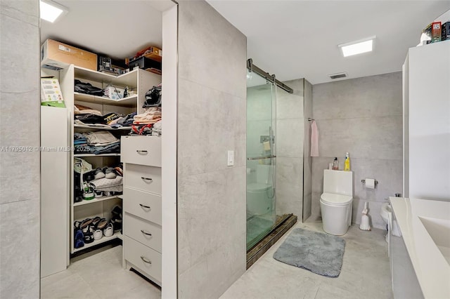 full bath featuring visible vents, toilet, a spacious closet, a shower stall, and a sink