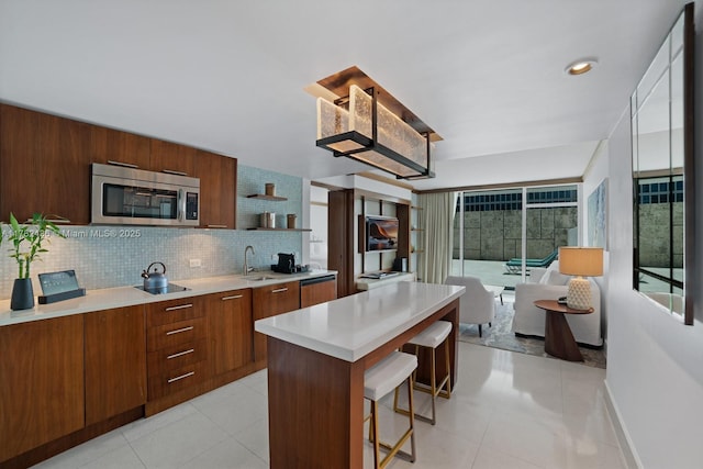 6801 Collins Ave Unit 604, Miami Beach, FL 33141 - kitchen featuring stainless steel microwave, modern cabinets, open shelves, light countertops, and a breakfast bar area