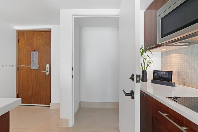 6801 Collins Ave Unit 604, Miami Beach, FL 33141 - kitchen featuring stainless steel microwave, decorative backsplash, light countertops, baseboards, and modern cabinets
