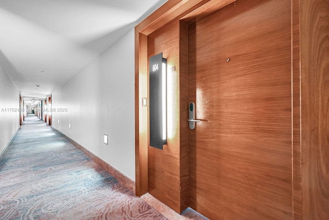 hallway featuring carpet floors and baseboards