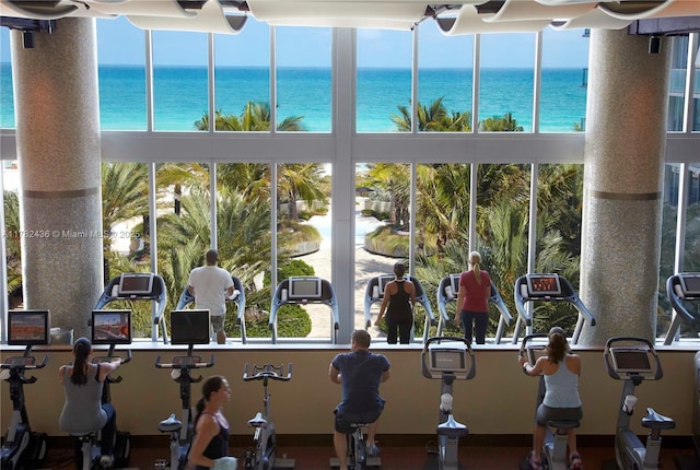 exercise room featuring a water view and a high ceiling