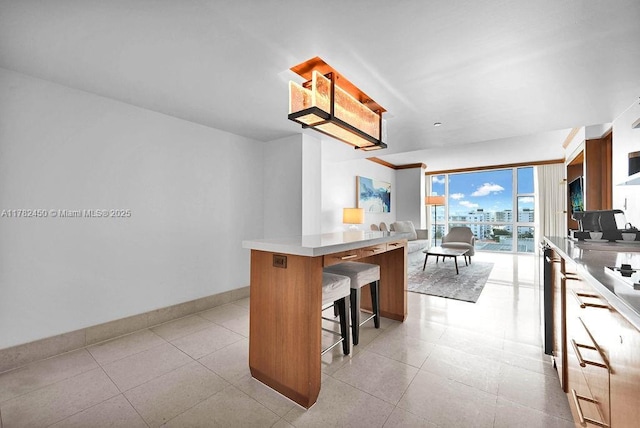 kitchen featuring a kitchen island, baseboards, open floor plan, a breakfast bar area, and light countertops