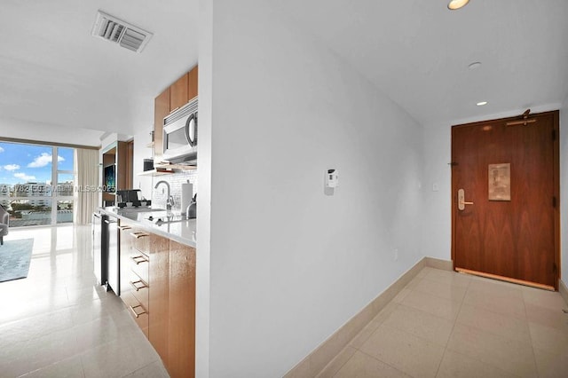 hall with visible vents, recessed lighting, baseboards, and light tile patterned flooring