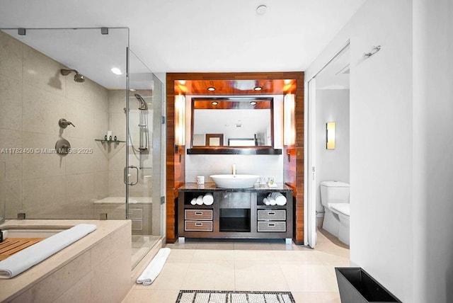 bathroom with tile walls, a shower stall, vanity, tile patterned floors, and toilet