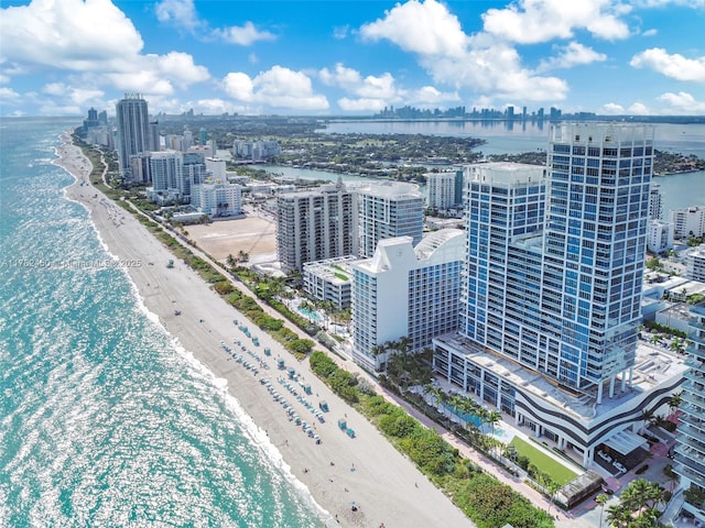 drone / aerial view featuring a water view, a city view, and a beach view