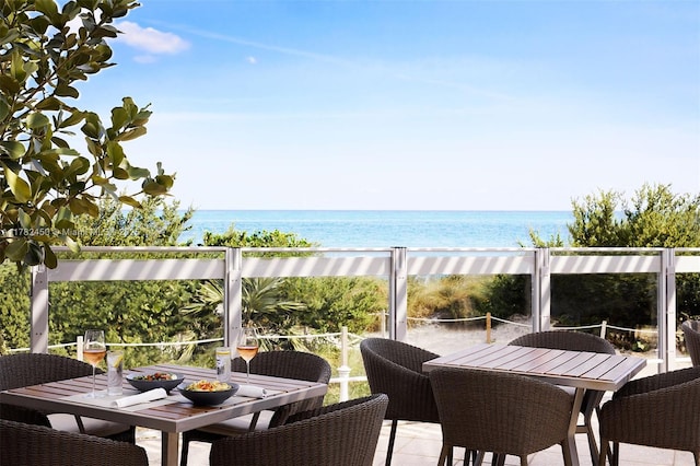 balcony with outdoor dining area and a water view