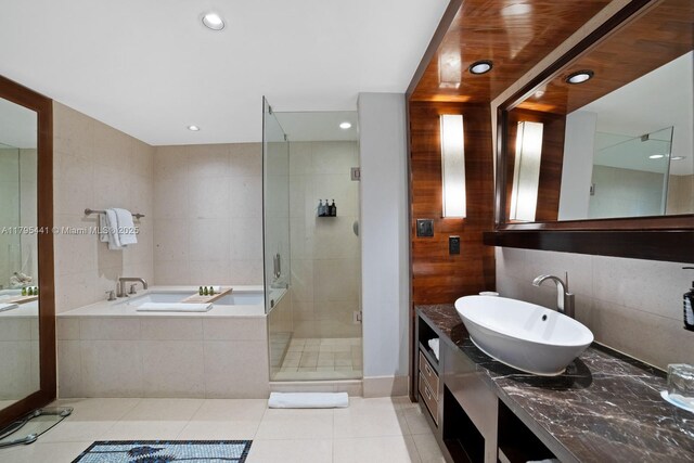 6801 Collins Ave Unit 605, Miami Beach, FL 33141 - bathroom with a bath, a shower stall, tile patterned floors, tile walls, and vanity