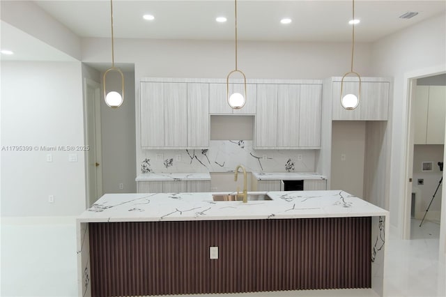 kitchen featuring backsplash, modern cabinets, a center island with sink, a sink, and recessed lighting