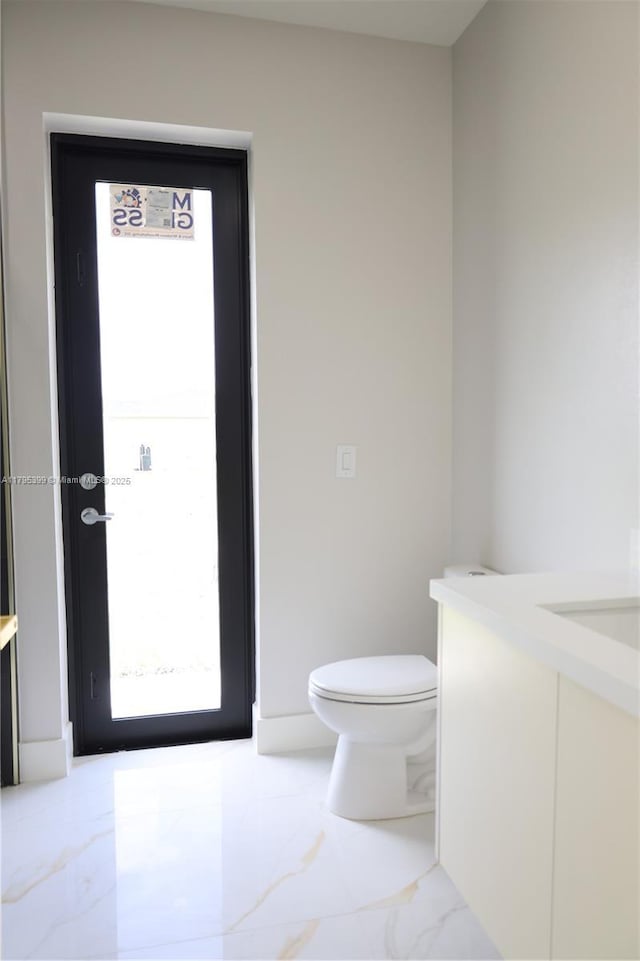 bathroom featuring toilet, marble finish floor, and vanity