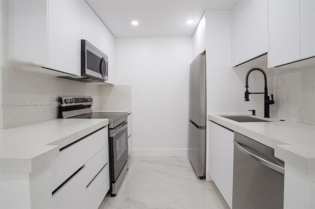 kitchen with baseboards, recessed lighting, white cabinetry, a sink, and appliances with stainless steel finishes