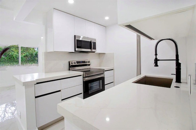 kitchen with a sink, modern cabinets, stainless steel appliances, and white cabinetry