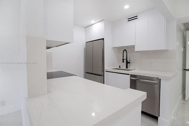 kitchen featuring white cabinets, appliances with stainless steel finishes, a sink, and marble finish floor