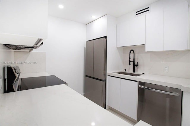 kitchen featuring decorative backsplash, light countertops, white cabinetry, a sink, and stainless steel appliances