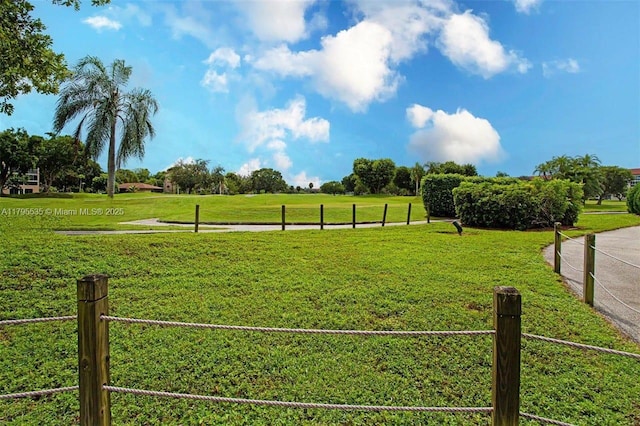 view of property's community featuring a lawn and fence