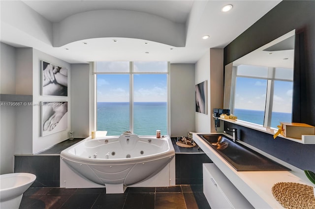 full bath featuring recessed lighting, a water view, vanity, and a tub with jets