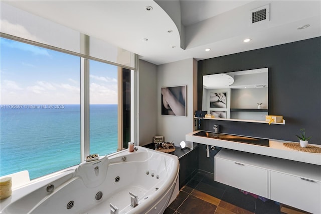 bathroom with visible vents, vanity, a jetted tub, recessed lighting, and a water view